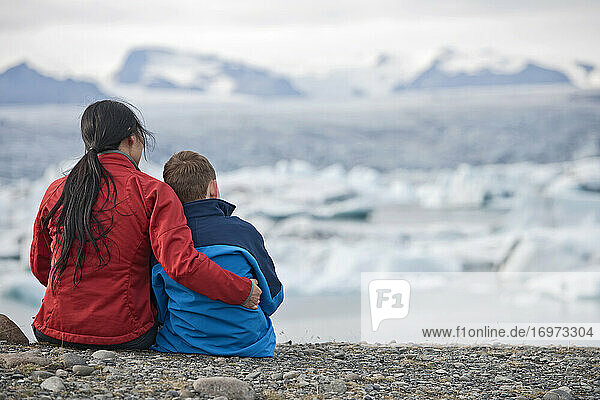 Mutter und Sohn betrachten eine Gletscherlagune in Island