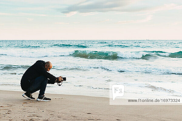 Man Photographing On A Beach At Sunset