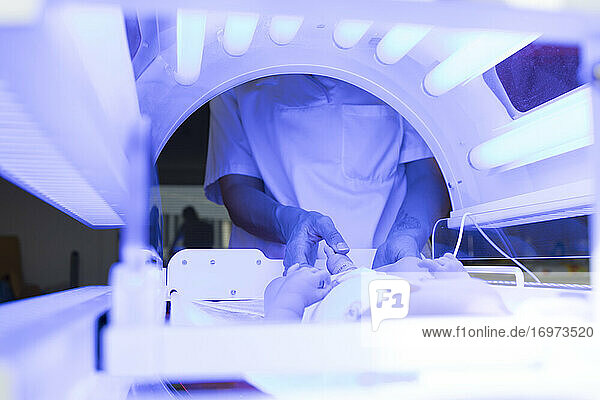 Neugeborenes in einem Inkubator. Eine Krankenschwester kümmert sich um das Baby