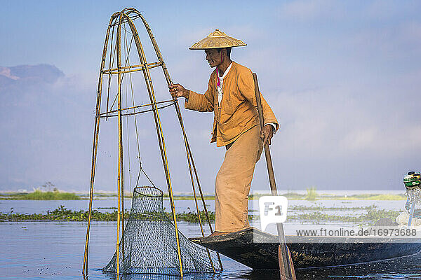 Side view of Intha fisherman with traditional conical fishing ne