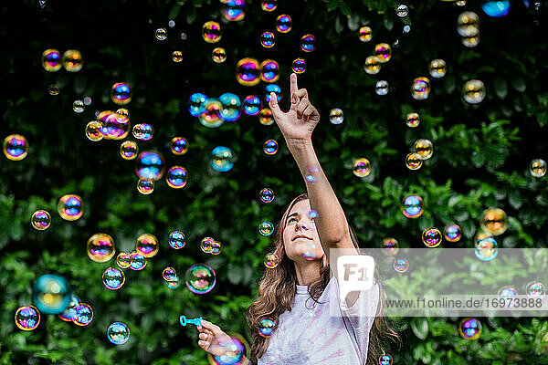 Teenager zeigt nach oben  während er von schillernden bunten Blasen umgeben ist