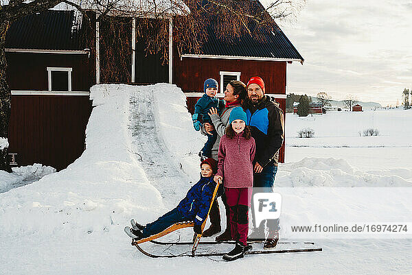 Schöne Familie stehen durch rote Scheune in norwegischen Landschaft im Schnee