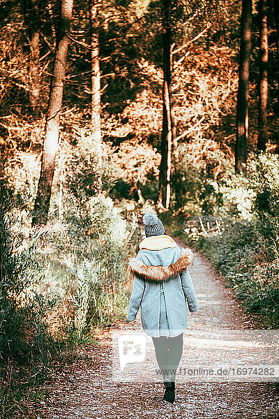 Frau in warmer Kleidung geht durch einen Wald