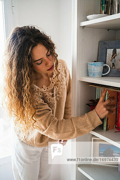 Junge Frau nimmt ein Buch aus dem Bücherregal