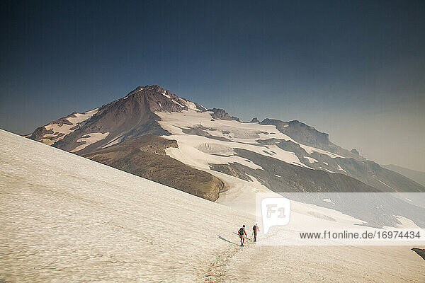 Two hikers climb towards the summit of Glacier Peak in Washington.