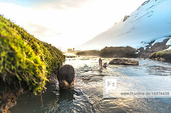 Frau entspannt sich im geothermischen Fluss Reykjadalur in Island