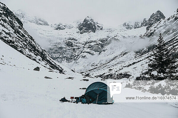 Camping mit blauem Zelt im Winter auf Schnee in der Schweiz