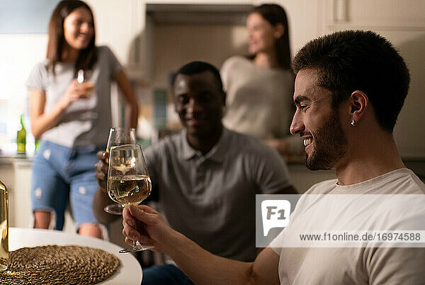 Glücklicher Mann genießt Wein bei einer Party mit Freunden