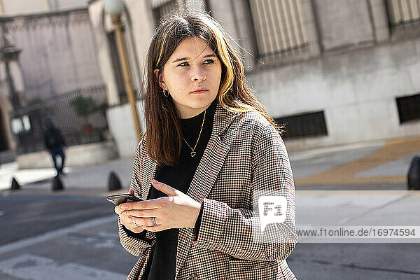 Mädchen mit einem Smartphone in den Händen auf einer Straße in Buenos Aires