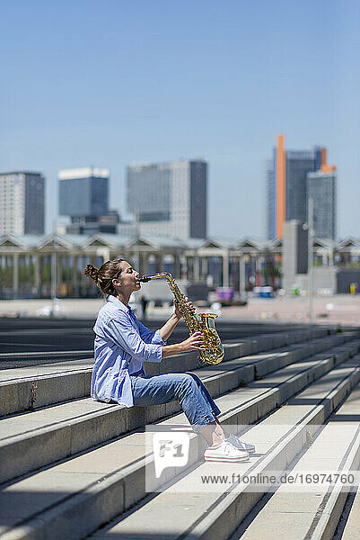 Frau mit Pferdeschwanz  die im Freien stehend ein Saxophon spielt