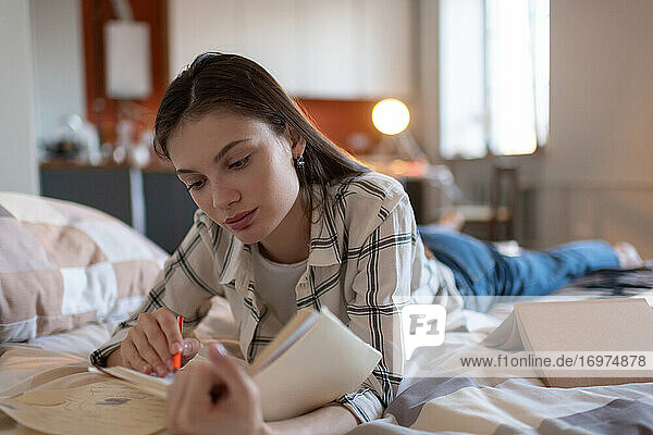 Mädchen studiert Notizen für Prüfung im Bett