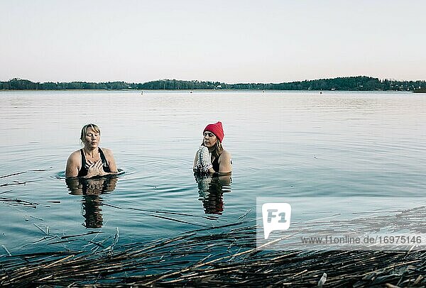 Zwei Frauen im ruhigen nordischen Meer schwimmen im kalten Wasser in Schweden