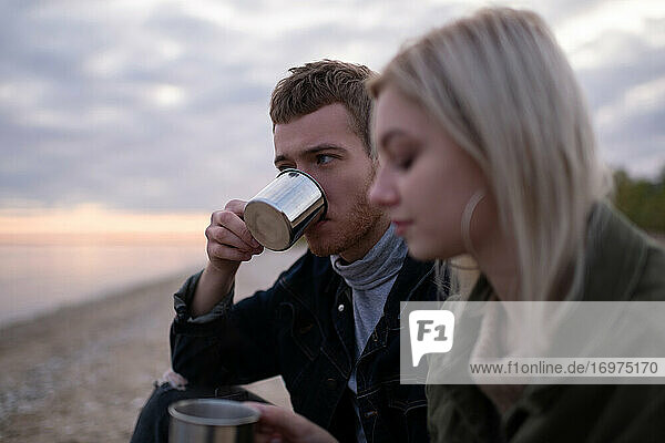 Mann trinkt Tee in der Nähe seiner Freundin auf dem Lande