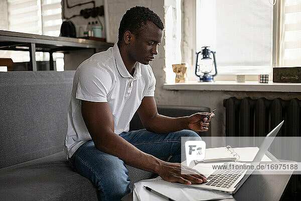 Schwarzer Mann macht Online-Bestellung auf Couch