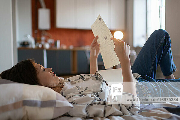 Mädchen liest Notizen für Prüfung im Bett