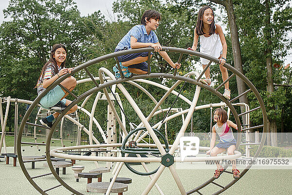 Vier Kinder klettern gemeinsam auf ein Spielgerät auf einem öffentlichen Spielplatz