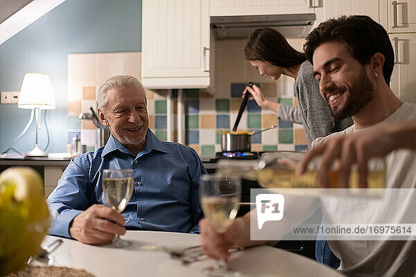 Glücklicher älterer Vater beobachtet Sohn beim Einschenken von Wein