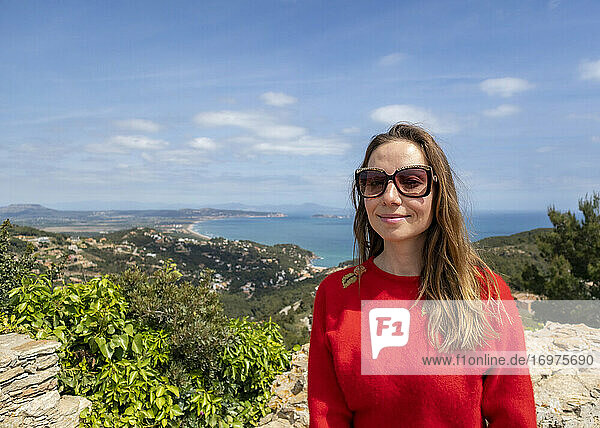 Fröhliches  rot gekleidetes Mädchen  das die Küste genießt und auf das Meer schaut
