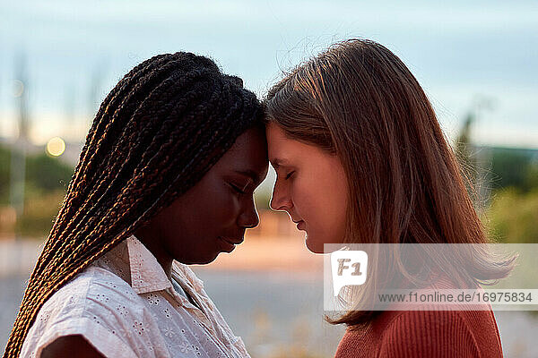 Zwei junge Frauen umarmen sich ernsthaft. Multiethnisches Konzept