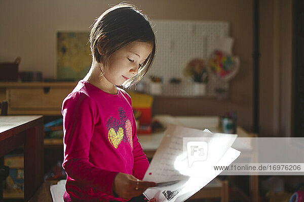 Ein kleines Mädchen in schönem Licht liest von einem Blatt Papier