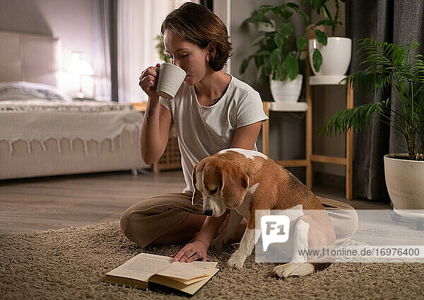 Hundebesitzer trinkt ein heißes Getränk und liest ein Buch