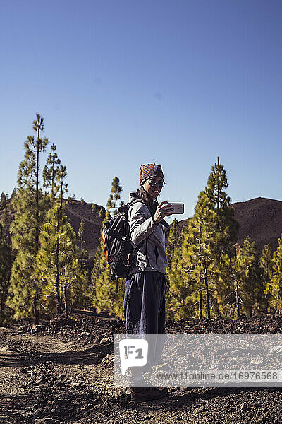 Starke Wanderin macht Selfie mit Smartphone im Bergwald