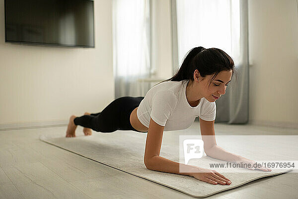 Junge Frau beim Planking auf der Matte zu Hause