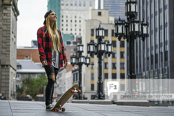 Stilvolle weibliche Millennials im städtischen Bereich mit Skateboard suchen
