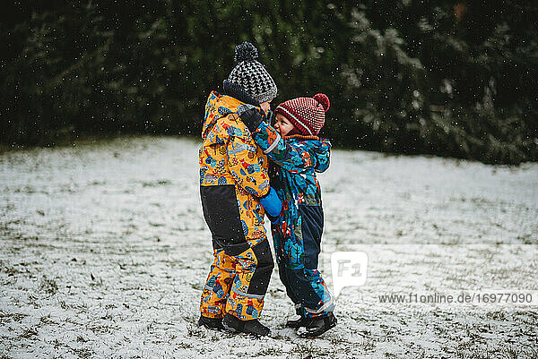 Kinder umarmen draußen an einem verschneiten Tag im Winter im Hinterhof