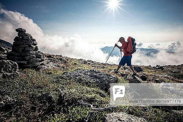 Man hiking through mountains with backpack and hiking poles