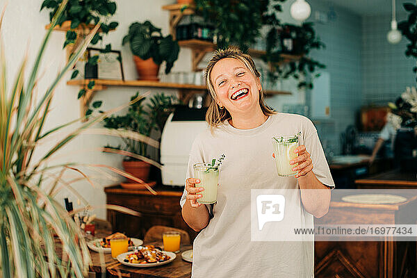 Frau mit Limonade  die in die Kamera lacht  während sie in einem Café steht