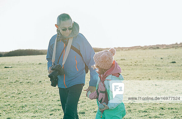grandfather holding his grand daughter's hand whilst walking outdoors