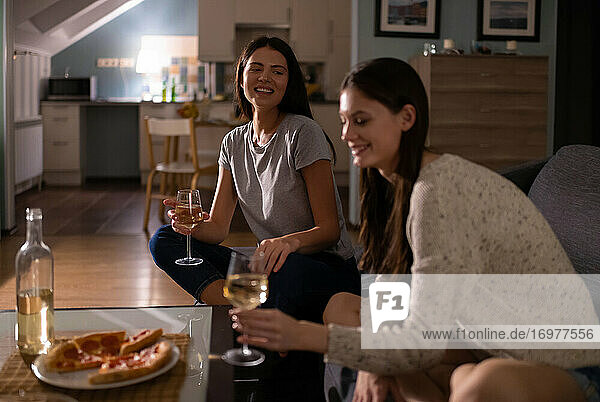 Glückliche Frauen kommunizieren während einer Weinparty auf der Couch