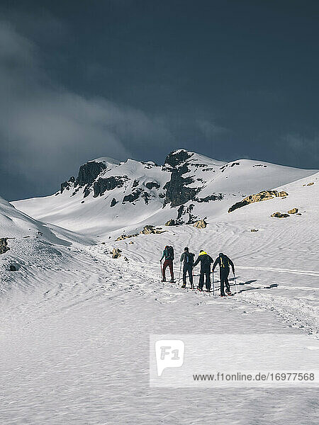 Wanderer auf Schneeschuhen auf einem Berggipfel vor schneebedeckten Gipfeln