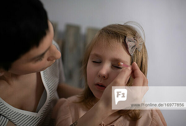 Mutter hilft Tochter beim Auftragen von Make-up