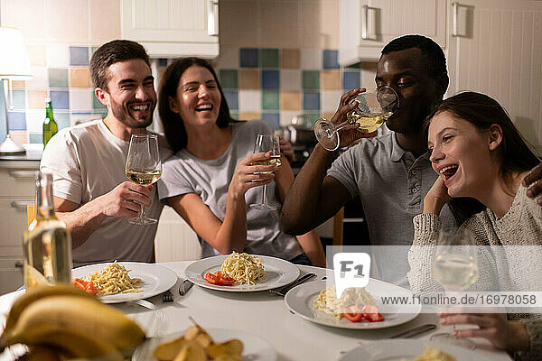 Schwarzer Mann trinkt Wein mit lachenden Freunden
