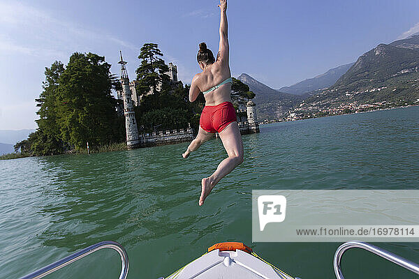 Eine Frau springt in einen See vor einer Festungsinsel in Italien