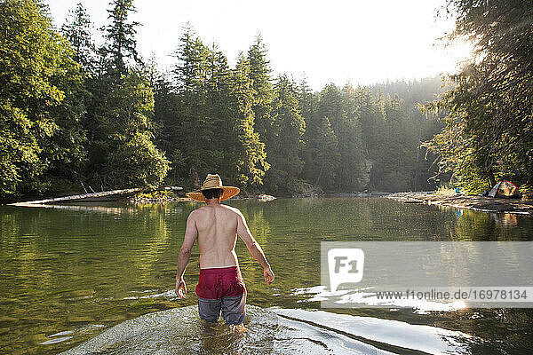 Ein junger Mann watet im Ohanapecosh River in Washington.