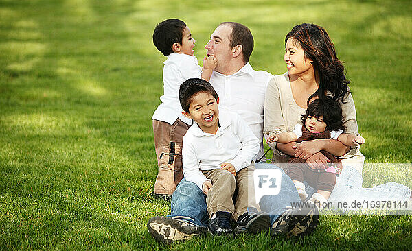 Familie sitzt im Gras im Park