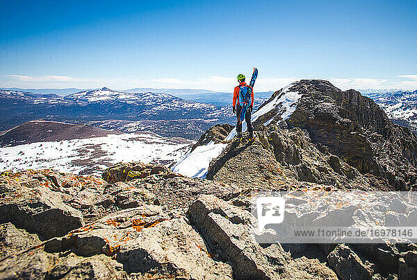 Mann mit Skiern auf dem Rücken geht in der Nähe des Gipfels eines Berges