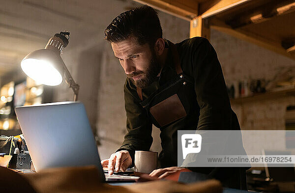 Handwerker mit Laptop auf dem Tisch in der Werkstatt
