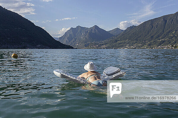 Ein Sonnenbadender  der auf einem Floß in einem See in Italien schwimmt