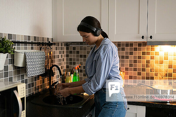 Frau bei der Hausarbeit und beim Abwasch in der Küche