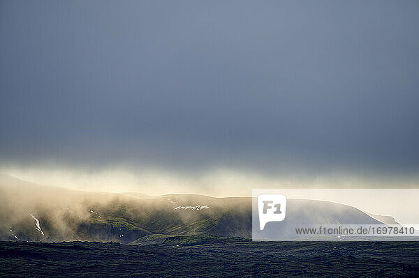 Hügeliges Terrain mit dichtem Nebel unter blauem Himmel