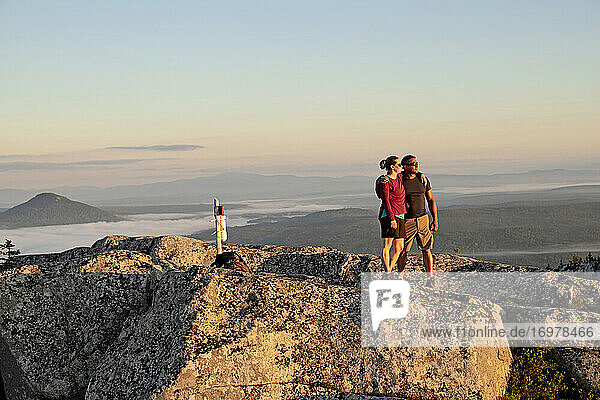 Couple embraces and hug after reaching summit of mountain in Maine