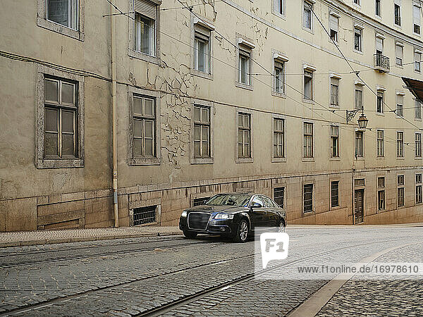 Schwarze Limousine fährt die Kopfsteinpflasterstraße in Lissabon hinauf
