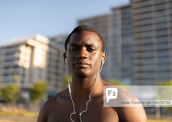Gutaussehender muskulöser schwarzer Sportler mit Kopfhörern im Freien