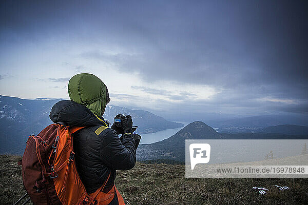 A young man takes a photo of the Columbia Gorge while hiking.