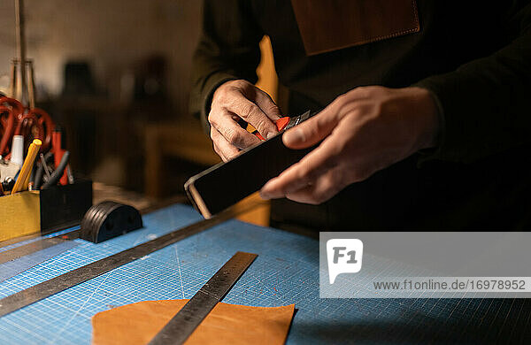 Geschnittener Handwerker beim Schärfen eines Messers in der Werkstatt