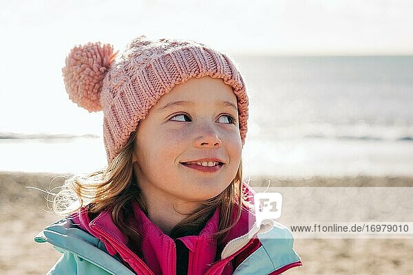 young girl looking cheekily over her shoulder at the beach in summer
